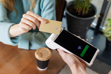 Portatif POS terminalindeki NFC banka kartını kullanarak kafenin içinde hazır kahve fincanı ile hızlı bir nakit çıkış yapmak için ellerini kapat.