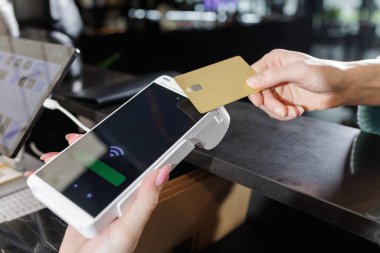 Müşteri, taşınabilir POS terminalindeki NFC banka kartını yanında laptop ve tablet ile parasız çıkış yapmak için kullanıyor.