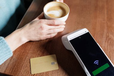 Temassız banka kartı ve portatif POS terminali kafeterya masasının üzerinde. Nakitsiz çıkış yaptıktan sonra el feneri ödeme konseptiyle birlikte.