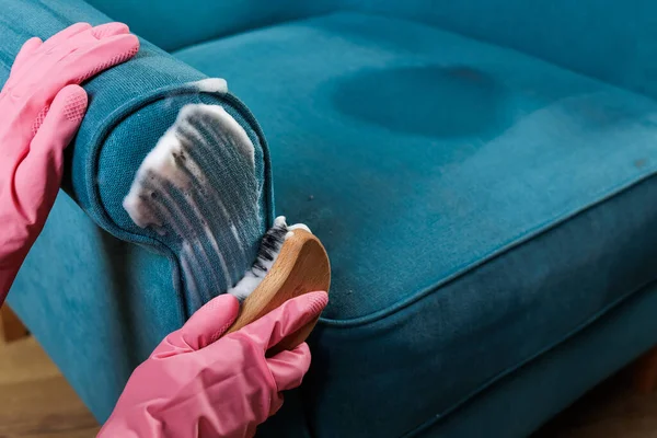 Pembe eldivenli, deterjan köpüklü, döşeme koltuğu köpüklü, ev temizleme şirketi için derin temizlik kumaşı olan bir işçiyi kapatın..