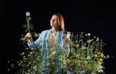 Yaratıcı çiçekçi kadın doğal dekor konsepti için arka planda yabani çiçek aranjmanıyla kozmos tutuyor.