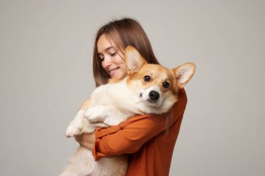 Mutlu bir kadının stüdyo portresi Corgi Dog 'a sarılıp kameraya bakarken refakatini ve sorumluluk sahibi köpek bakımını gösteriyor.