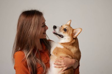 Corgi 'yi kucağında tutan kadının portresi neşe ve güçlü bir köpek sahibi olduğunu gösteriyor.