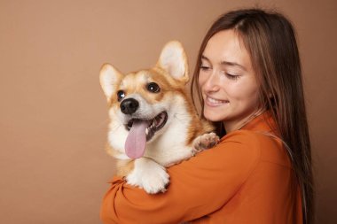 Stüdyo, gülümseyen bir kadının Corgi Dog 'a sarıldığı ve arkadaşlığın rahatlık, güven ve sorumluluk sahibi bir hayvan bakımı sergilediği yakın plan.