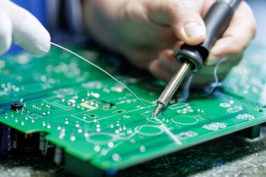 Elektronik fabrikasındaki yeşil baskılı devre kartındaki işçi el lehimleme bileşenlerini tamir ve montaj konsepti için kapat