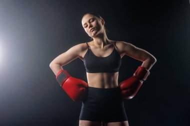 Studio portrait of a woman boxer in red gloves on dark background with copy space, suitable for fitness training websites, banners, ads, and social posts.