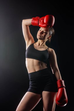 Kırmızı eldivenli kendine güvenen kadın boksörün stüdyo portresi, fitness web sitesi afişi veya sosyal kampanya için fotokopi alanı olan koyu arkaplan.