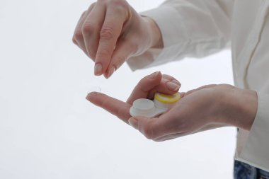 Parmak uçlarında kontak lens, beyaz arkaplanda depolama çantası, optometri web sitesi afişi veya lens hijyeni ve görme düzeltmesi hakkında eğitim için ideal eller.