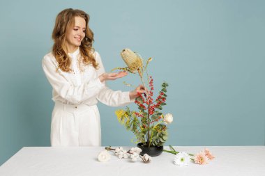 Kurumuş ve taze botanikli Kenzan kullanarak heykeltraş tasarımı yapan kadın. Çiçekçilik, kültürel dekor pazarlama ve yaşam tarzı kampanyaları için ideal..