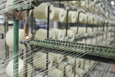Tekstil imalatı, endüstriyel otomasyon ve üretim pazarlama görselleri için ideal, otomatik dokuma makinesine beslenen iplikli iplikler..