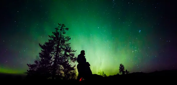 Sylwetki osób nad aurora borealis — Zdjęcie stockowe