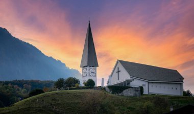 Dağ manzaralı kilise binası. Arka planda güzel bir günbatımı gökyüzü var.
