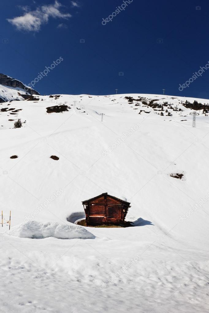 Wooden cottage between snowy mountains