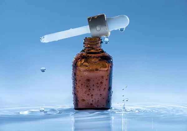 Återfuktande anti age serum på blått vatten bakgrund med pipett och stänk — Stockfoto