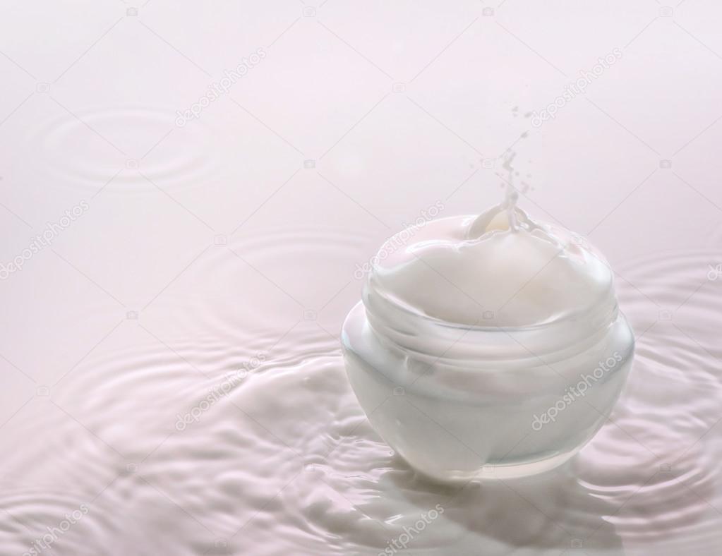 Moisturizing cosmetic  cream on the pink milk background with milk splash and drops