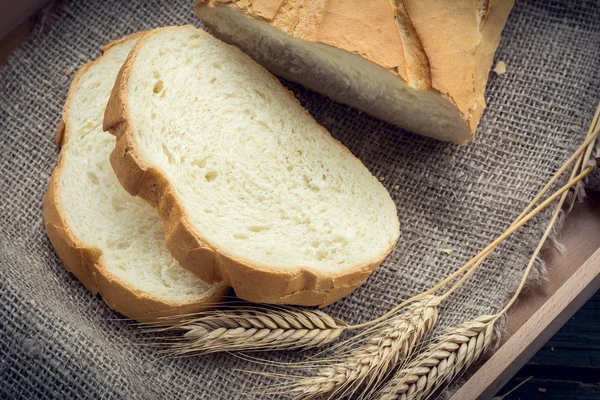 Fatia de pão fresco com poucas espiguetas de trigo — Fotografia de Stock