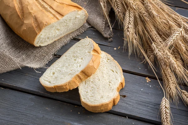 Pão fresco com espiguetas de trigo — Fotografia de Stock