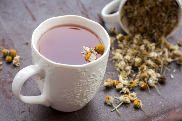 Tasse de thé à la camomille avec des fleurs de camomille séchées sur fond — Photo