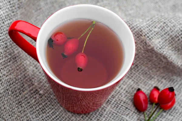 Tasse de thé avec rose chien sur fond lin, mise au point sélective — Photo