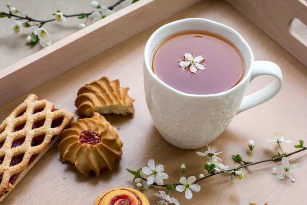 Färska söta smördeg med kopp svart te i trä facket — Stockfoto