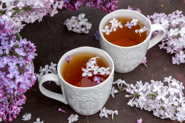 Tasse de thé avec des fleurs lilas et des branches de lilas sur fond — Photo