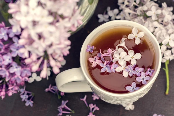 Сирень цветущая ветви и чашка черного чая. Винтажный тон — стоковое фото