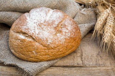 Ev yapımı yuvarlak ekmek buğday arka plan üzerinde demet bezle üzerine