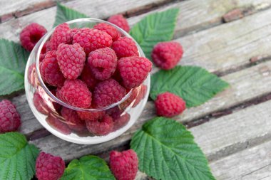 Tasty ahududu saydam vazo içinde ahşap bir masa arıyorum.