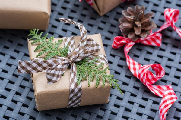 Pequeña caja de regalo envuelta en papel reciclado con lazo de cinta y ramas de thuja — Foto de Stock