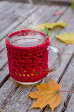 Ahşap arka plan üzerinde sıcak çay ile kırmızı örme Kupası