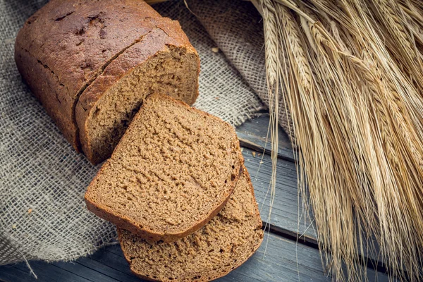 Ржаной хлеб с шипами ячменя на деревянном фоне — стоковое фото