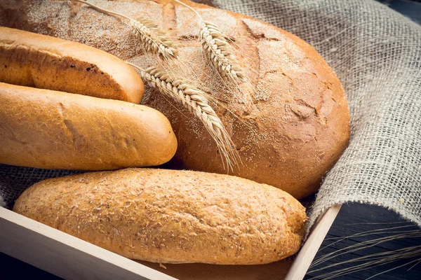 Свежий хлеб с колосьями пшеницы на деревянном подносе — стоковое фото