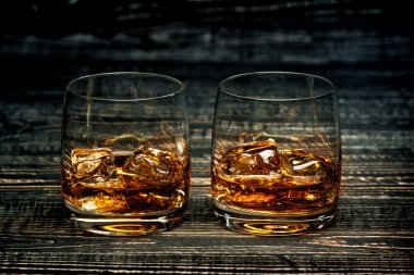 whiskey with ice on a black wooden background clipart