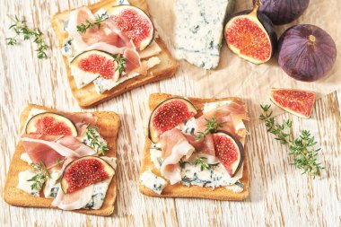 Mavi peynirli tost, jambon ve beyaz bir masada taze incir..