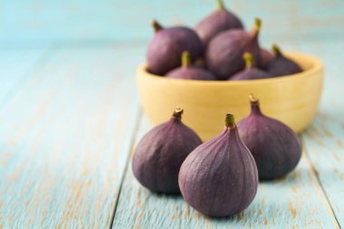 Olgun incirler ahşap bir kasede mavi bir masada fotokopi alanı ile.