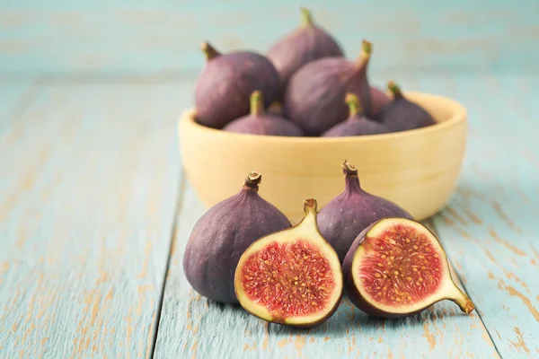 ripe figs in a wooden bowl on a blue table with copy space. group of figs in a bowl  on rustic blue wooden table.