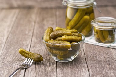 Şeffaf cam kasede turşu. Tahta bir masada salatalıklı salatalıklar, seçici bir odak..