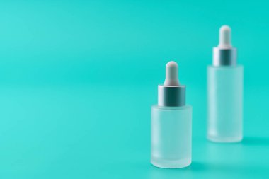 Kozmetik ya da pipetli tıbbi cam şişe. Deri bakımı konsepti. Doğal kozmetik ürünleri, saç ve cilt bakımı için serum. Mavi arka planda iki tıbbi serum şişesi veya hyaluronik asit..