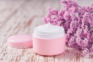 Doğal nemlendirici ya da vücut losyonu, ahşap bir masada yaşlanma karşıtı cilt bakımı konsepti. Tahta masadaki hassas cilt kremi için plastik pembe kavanoz..