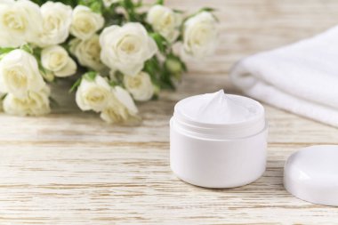 Doğal yüz kremi ya da losyona duyarlı cilt, organik kozmetik ürünler beyaz güllerin arka planındaki deriyi nemlendirir..