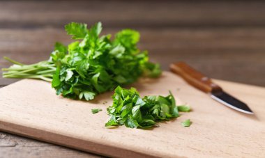 Kesme tahtasının üzerinde taze doğranmış organik maydanoz yaprakları, seçici odak noktası, köy tarzı..