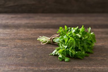 Kırsal ahşap arka planda bir demet taze organik maydanoz, seçici bir odak. Metin için alanı kopyala.