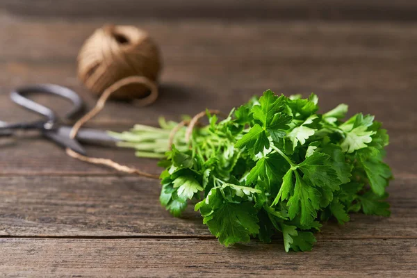 bunch of fresh  parsley on a wooden table with scissors and rope. Selective focus, rustic style.