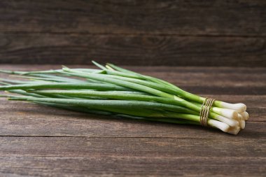 Tahta masada bir demet yeşil soğan, seçici odaklanma. Genç yeşil soğan. Taze soğan..