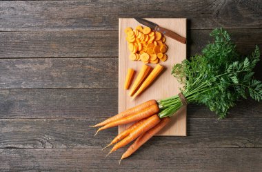 Havuç doğra. Kesme tahtasındaki dilimlenmiş organik havuçlar, üst manzara, köy tarzı..