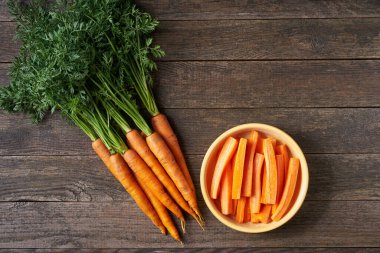 Tahta bir kasede taze havuç, masanın üstünde, üst görünümde, metin için boşluk kopyala.