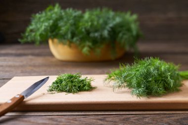 Kesme tahtasında taze doğranmış organik dereotu yaprakları, seçici odak noktası, köy tarzı..