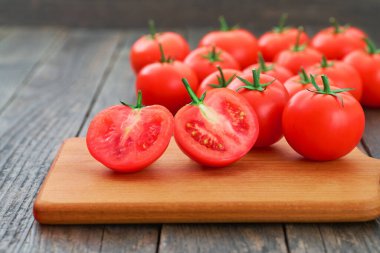 Kesme tahtasında bütün ve dilimlenmiş kırmızı domatesler..