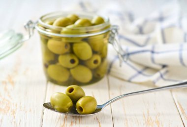 Tahta bir arka planda salamura edilmiş zeytin kavanozu aç, seçici odaklanma.