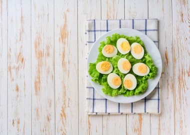 Beyaz bir masada yarı yarıya haşlanmış taze yumurta, üst manzara. Boşluğu kopyala.